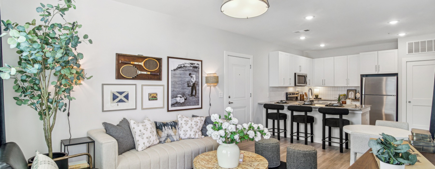 living room in the model with a couch and view of the kitchen 