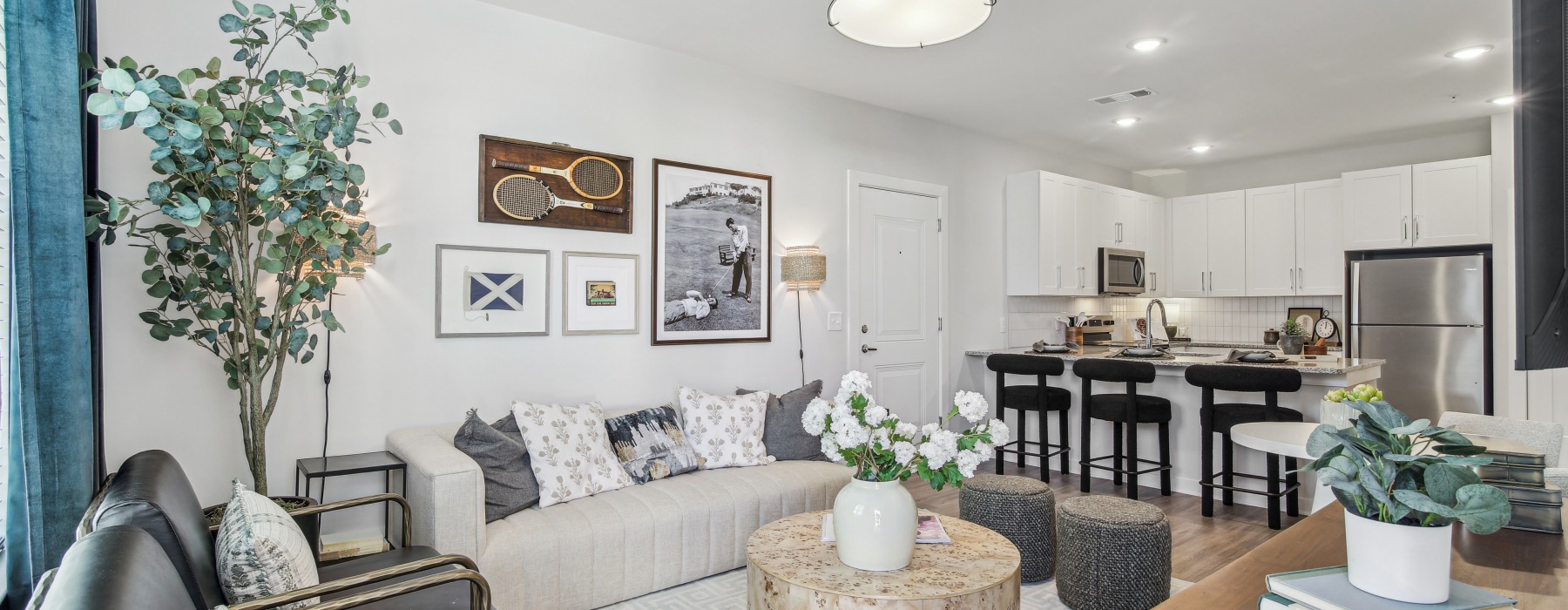 living room in the model with a couch and view of the kitchen 